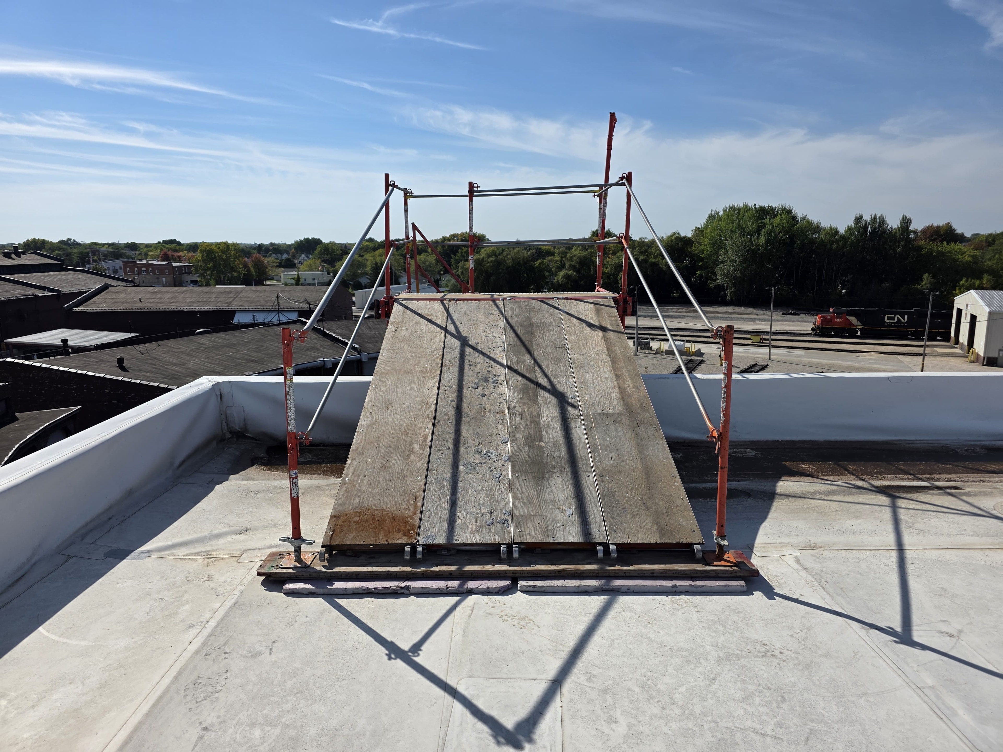 A frame scaffold stair tower on the exterior of a building with a plywood enclosure attached to it